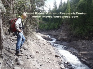 6-9-13: The river has cut a 10-m-deep canyon through the May 31 debris flow deposit.Dave is standing on the margin of the 5/31/13 deposit. Chris Magirl photo.
